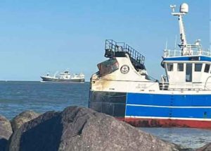Efter en dramatisk grundstødning ved Nordmolen ved Hirtshals Havn - er besætningen nu reddet sikkert i land med helikopter – nu venter det afgørende øjeblik med højvande og en kontrolleret »warping«. foto: Erik Kronquist