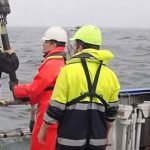 Forsker Kasper Urup Kjeldsen (rødt regntøj) hiver en boreprøve fra bunden af Aarhus Bugt ombord på forskningsskibet Aurora. I prøven gemmer sig mikroorganismer, som bærer rundt på en velbevaret hemmelighed. (Foto: Screendump fra video af Christof Pearce)